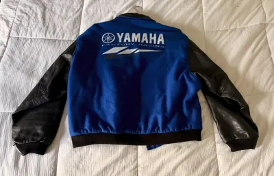 Yamaha Factory Racing varsity-style jacket featuring a blue wool body with embroidered back logo and black leather sleeves.