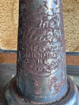 Sale Photo Thumbnail #189: A vintage glass oil dispenser bottle featuring a textured base and a metal pouring spout. The metal spout is embossed with "The Huffman Mfg. Co. Dayton, Ohio, Pat. Pend." and shows significant surface rust and patina consistent with age and garage use. Th