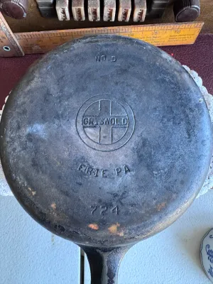 Sale Photo Thumbnail #264: An authentic vintage Griswold No. 5 cast iron skillet, model number 724 G. Made in Erie, Pennsylvania, USA. Features the classic Griswold small logo marking on the bottom. The skillet shows signs of age and use, including surface wear, some build-up, and 