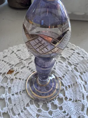 Sale Photo Thumbnail #319: A beautiful vintage bud vase featuring a purple or amethyst-colored glass body with cut-to-clear geometric patterns and elegant gold-toned painted trim bands. The piece has a flared rim, a bulbous body, and a pedestal base. It is in good vintage condition