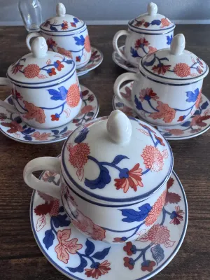 Sale Photo Thumbnail #61: A beautiful set of 5 vintage lidded tea cups with matching saucers by Fitz and Floyd. Each piece features a vibrant hand-decorated floral pattern in shades of blue, orange, and red. The bottoms are marked with the 'FF' copyright stamp, and one cup retains