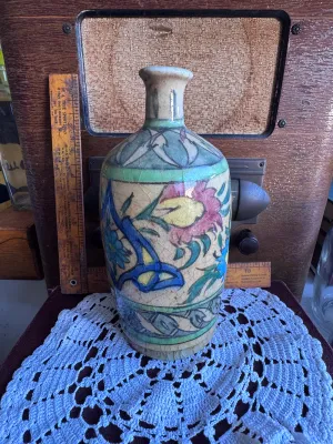 Sale Photo Thumbnail #73: An antique hand-painted earthenware pottery vase or bottle, featuring traditional floral and foliate motifs in vibrant blue, green, yellow, and red glazes over a cream slip ground. The piece exhibits a heavily crackled glaze texture throughout, characteri