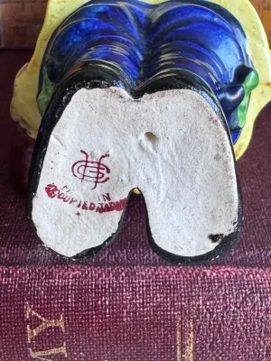 Sale Photo Thumbnail #197: A vintage hand-painted ceramic figurine depicting an Asian boy in traditional yellow and blue attire holding a banjo-like instrument. The base is stamped with a red maker's mark and reads 'Made in Occupied Japan', dating this piece to the post-WWII era (1