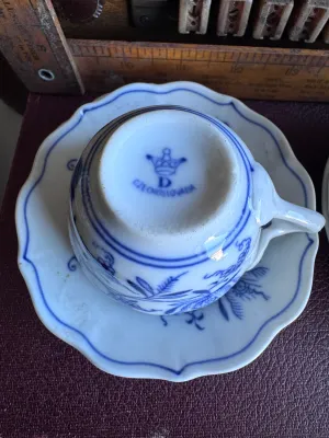 Sale Photo Thumbnail #35: A collection of four blue and white porcelain tea cups with matching saucers in the classic Blue Onion pattern. 

This lot includes:
- Two larger tea cups and saucers marked on the bottom by Hutschenreuther (Selb, Germany).
- Two smaller demitasse-sized c