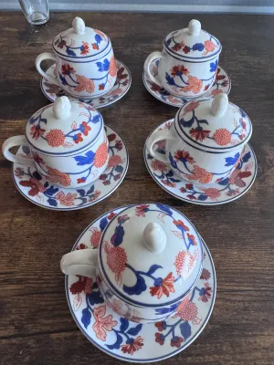 Sale Photo Thumbnail #60: A beautiful set of 5 vintage lidded tea cups with matching saucers by Fitz and Floyd. Each piece features a vibrant hand-decorated floral pattern in shades of blue, orange, and red. The bottoms are marked with the 'FF' copyright stamp, and one cup retains