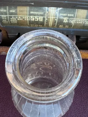 Sale Photo Thumbnail #306: A vintage clear glass one-pint milk bottle featuring embossed lettering. One side reads 'Universal Store Bottle / Sealed 1-11-14 / One Pint Liquid / Reg. U.S. Pat. Off.' and features vertical ribbing. The reverse side is embossed with 'Store Bottle' and a
