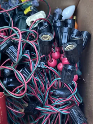 Sale Photo Thumbnail #118: A large estate collection of vintage Christmas lighting. Includes multiple green and red/pink insulated wire light strings with black sockets, a vintage red cardboard box of 'Twinkling Lamps' by World Wide, and a large assortment of loose ceramic and pain