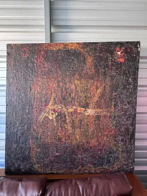 Sale Photo Thumbnail #201: A large, heavily textured abstract mixed media painting on canvas. The piece features a dark, moody color palette dominated by deep browns, blacks, and purples, with contrasting highlights of red, orange, and yellow. The surface exhibits a thick, impasto-