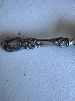 Sale Photo Thumbnail #66: An elegant antique cake or pie server featuring a highly detailed, ornate sterling silver handle with floral and scroll motifs. The server blade is constructed of polished metal (likely silver-plated or stainless steel). It measures approximately 10 inche