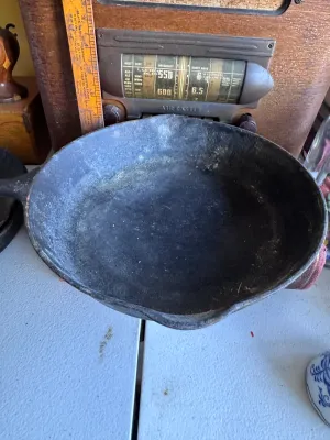Sale Photo Thumbnail #269: A vintage Griswold No. 7 cast iron skillet, marked with the classic Griswold logo, 'ERIE PA., U.S.A.', and model number '701 E'. Features dual pour spouts and a teardrop handle. The skillet shows signs of age and use, including surface buildup, minor rust