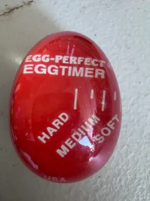 Sale Photo Thumbnail #287: Vintage Egg-Perfect Eggtimer. This color-changing egg timer sits in the pot with your eggs and darkens to indicate soft, medium, or hard-boiled stages. Marked 'USA' on the bottom edge. Made of temperature-sensitive plastic/resin. Shows some light surface 