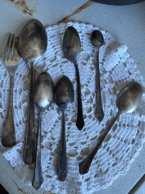 Sale Photo Thumbnail #280: An assortment of 7 vintage silverplated flatware pieces, including five spoons of various sizes, one serving spoon, and one pickle/cold meat fork. The pieces feature various ornate floral and classic handle patterns. Notable markings visible on the backs 