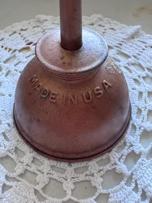 Sale Photo Thumbnail #329: A vintage thumb pump oiler can manufactured by Eagle. Features a copper-plated finish with embossed lettering reading "EAGLE" on one side and "MADE IN USA" on the other. Shows a nice aged patina with some light surface wear, minor scuffs, and residue cons