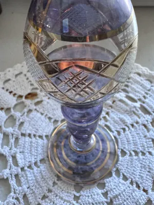 Sale Photo Thumbnail #318: A beautiful vintage bud vase featuring a purple or amethyst-colored glass body with cut-to-clear geometric patterns and elegant gold-toned painted trim bands. The piece has a flared rim, a bulbous body, and a pedestal base. It is in good vintage condition