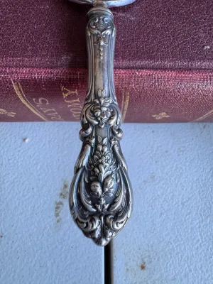 Sale Photo Thumbnail #65: An elegant antique cake or pie server featuring a highly detailed, ornate sterling silver handle with floral and scroll motifs. The server blade is constructed of polished metal (likely silver-plated or stainless steel). It measures approximately 10 inche