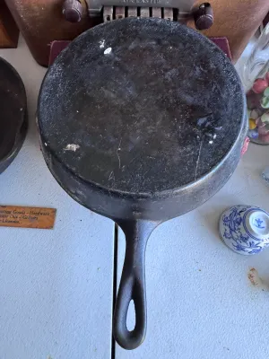 Sale Photo Thumbnail #275: A vintage cast iron skillet featuring the distinctive teardrop-shaped handle hole and number marking characteristic of the Chicago Hardware Foundry (CHF), made in North Chicago, Illinois. The bottom shows a raised number '4' and a diamond mark. The skille
