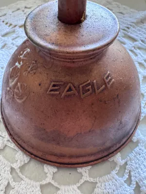 Sale Photo Thumbnail #328: A vintage thumb pump oiler can manufactured by Eagle. Features a copper-plated finish with embossed lettering reading "EAGLE" on one side and "MADE IN USA" on the other. Shows a nice aged patina with some light surface wear, minor scuffs, and residue cons