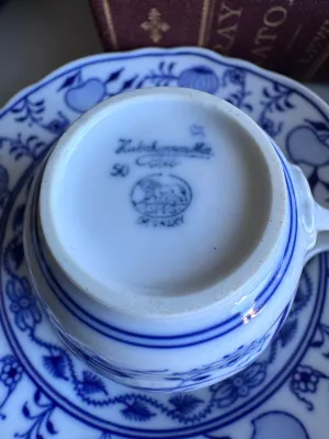 Sale Photo Thumbnail #34: A collection of four blue and white porcelain tea cups with matching saucers in the classic Blue Onion pattern. 

This lot includes:
- Two larger tea cups and saucers marked on the bottom by Hutschenreuther (Selb, Germany).
- Two smaller demitasse-sized c