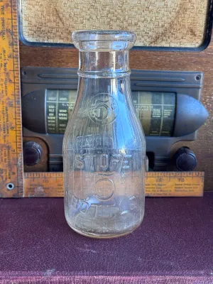 Sale Photo Thumbnail #305: A vintage clear glass one-pint milk bottle featuring embossed lettering. One side reads 'Universal Store Bottle / Sealed 1-11-14 / One Pint Liquid / Reg. U.S. Pat. Off.' and features vertical ribbing. The reverse side is embossed with 'Store Bottle' and a