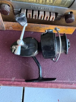 Sale Photo Thumbnail #281: A vintage Mitchell spinning fishing reel featuring a classic black finish. The body is marked with 'Made in France'. It shows some signs of wear and age-appropriate use, including light surface dust and minor scuffs, but remains in solid cosmetic conditio
