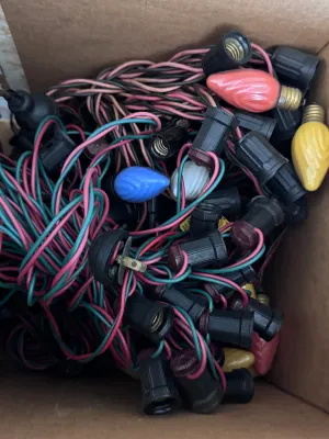 Sale Photo Thumbnail #110: A large estate collection of vintage Christmas lighting. Includes multiple green and red/pink insulated wire light strings with black sockets, a vintage red cardboard box of 'Twinkling Lamps' by World Wide, and a large assortment of loose ceramic and pain