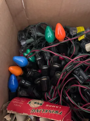 Sale Photo Thumbnail #117: A large estate collection of vintage Christmas lighting. Includes multiple green and red/pink insulated wire light strings with black sockets, a vintage red cardboard box of 'Twinkling Lamps' by World Wide, and a large assortment of loose ceramic and pain