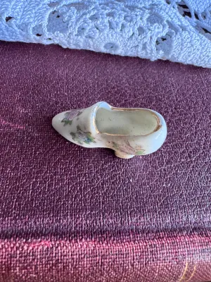 Sale Photo Thumbnail #238: A vintage miniature porcelain shoe figurine featuring delicate hand-painted floral details and gold-gilded trim. The bottom is stamped in red with 'MADE IN OCCUPIED JAPAN', dating this piece to the post-WWII occupation period (1945–1952). It is in good 