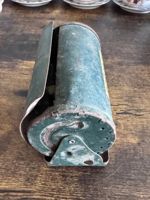 Sale Photo Thumbnail #225: A vintage Bob-Bet Bait Box featuring a cylindrical green metal body on a stand. The front label reads, "BOB-BET BAIT BOX - JUST HALF A TURN AND THERE'S YOUR WORM." The item shows significant vintage wear, including rust, paint loss, and surface grime cons