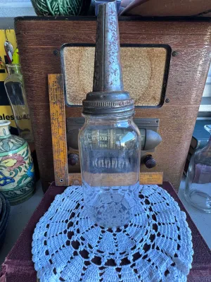 Sale Photo Thumbnail #188: A vintage glass oil dispenser bottle featuring a textured base and a metal pouring spout. The metal spout is embossed with "The Huffman Mfg. Co. Dayton, Ohio, Pat. Pend." and shows significant surface rust and patina consistent with age and garage use. Th