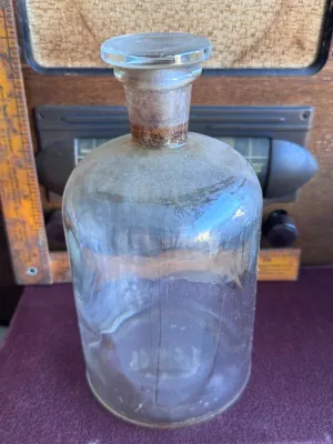 Sale Photo Thumbnail #343: An antique or vintage clear glass apothecary/chemical bottle featuring its original ground glass stopper. The bottom is embossed with 'T.C.W. CO. U.S.A.', indicating it was manufactured by the T.C. Wheaton Glass Company in Millville, New Jersey, USA. The 