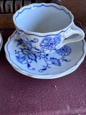 Sale Photo Thumbnail #36: A collection of four blue and white porcelain tea cups with matching saucers in the classic Blue Onion pattern. 

This lot includes:
- Two larger tea cups and saucers marked on the bottom by Hutschenreuther (Selb, Germany).
- Two smaller demitasse-sized c