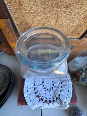 Sale Photo Thumbnail #255: A vintage clear glass jar featuring the embossed text "Ann's House of Nuts" on the bottom. The jar has a rectangular body tapering slightly towards the neck with a wide, rounded rim. It stands approximately 9.5 inches tall based on the adjacent ruler. Goo