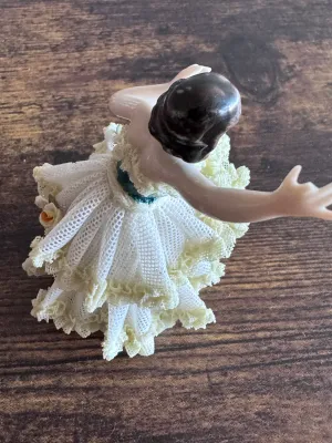 Sale Photo Thumbnail #89: A vintage Capodimonte porcelain figurine depicting a graceful ballerina in a delicate, multi-layered yellow and white porcelain lace tutu. The figure features hand-painted details, including a green bodice, a pink rose accent on the skirt, and gold gilt h