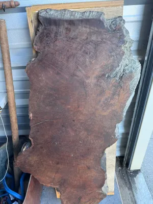 Sale Photo Thumbnail #26: A substantial, thick-cut live edge redwood burl wood slab featuring rich reddish-brown tones, prominent growth rings, and natural textured bark edges. This rustic piece is ideal for a custom coffee table, console top, or wall art. It measures approximatel