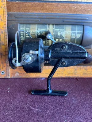 Sale Photo Thumbnail #282: A vintage Mitchell spinning fishing reel featuring a classic black finish. The body is marked with 'Made in France'. It shows some signs of wear and age-appropriate use, including light surface dust and minor scuffs, but remains in solid cosmetic conditio