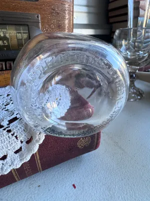 Sale Photo Thumbnail #246: A vintage clear glass liquor decanter or bottle featuring the embossed text on the bottom: "FEDERAL LAW FORBIDS SALE OR REUSE OF THIS BOTTLE". This phrase dates the bottle to the post-Prohibition era, specifically between 1935 and 1964. The bottom also fe