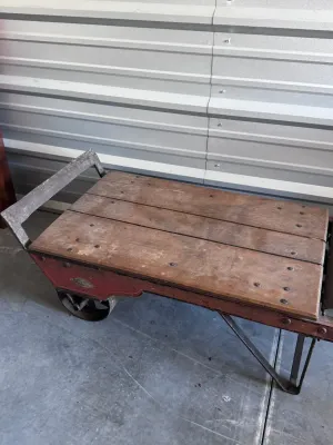 Sale Photo Thumbnail #15: An authentic antique Fairbanks wooden hand truck scale, combining a heavy-duty warehouse dolly with an integrated mechanical platform scale. Features a sturdy wood-plank bed, curved wooden handles, cast iron wheels, and the original mechanical weighing me
