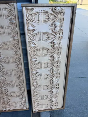 Sale Photo Thumbnail #30: A pair of decorative wall panels featuring highly detailed Gothic Revival style plaster relief friezes. The panels showcase intricate tracery, foliate motifs, and architectural elements finished in an off-white/cream tone. Each plaster section is mounted 