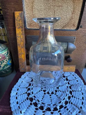 Sale Photo Thumbnail #244: A vintage clear glass liquor decanter or bottle featuring the embossed text on the bottom: "FEDERAL LAW FORBIDS SALE OR REUSE OF THIS BOTTLE". This phrase dates the bottle to the post-Prohibition era, specifically between 1935 and 1964. The bottom also fe