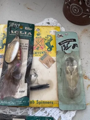 Sale Photo Thumbnail #322: A collection of vintage fishing lures in their original packaging. This lot includes:
- Two Mepps Aglia 'Killer' Original French Spinners by Sheldons' Inc. (Antigo, Wisconsin), featuring natural hair dressings.
- One Herter's Mitchell Scarab Spinners card