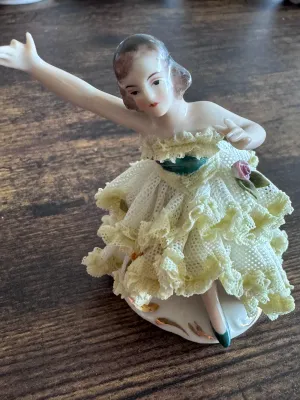 Sale Photo Thumbnail #87: A vintage Capodimonte porcelain figurine depicting a graceful ballerina in a delicate, multi-layered yellow and white porcelain lace tutu. The figure features hand-painted details, including a green bodice, a pink rose accent on the skirt, and gold gilt h