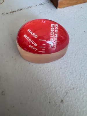 Sale Photo Thumbnail #288: Vintage Egg-Perfect Eggtimer. This color-changing egg timer sits in the pot with your eggs and darkens to indicate soft, medium, or hard-boiled stages. Marked 'USA' on the bottom edge. Made of temperature-sensitive plastic/resin. Shows some light surface 