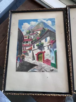 Sale Photo Thumbnail #214: A beautiful pair of original mid-century watercolor paintings depicting vibrant street scenes of Taxco, Mexico. Each piece is signed by the artist 'Max V.' in the lower corner. One painting features a cobblestone street leading toward the iconic Santa Pri