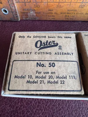 Sale Photo Thumbnail #296: A collection of vintage barber/hair clipper replacement blades in their original cardboard packaging. Includes:
- One Oster Unitary Cutting Assembly No. 50 (for use on Models 10, 20, 111, 21, and 22)
- One Oster Unitary Cutting Assembly No. 50 (for use on