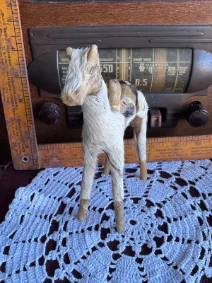 Sale Photo Thumbnail #186: A vintage handmade camel figurine covered in genuine animal fur with leather details forming the saddle and face. This folk art piece stands approximately 6 inches tall and features simple wooden dowel legs. Shows some age-related wear to the leather and 