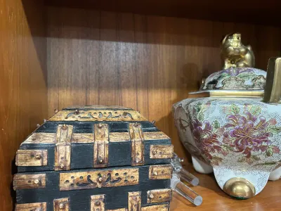 Sale Photo Thumbnail #11: Small rustic wooden treasure chest box with metal band detailing alongside a Satsuma-style porcelain censer featuring floral motifs and a gold foo dog finial.