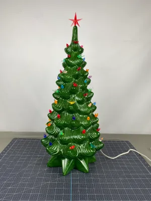 Vintage green ceramic Christmas tree with multi-colored plastic bulb inserts and a red star topper, shown illuminated.