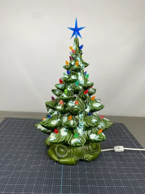 Vintage ceramic Christmas tree with snow-tipped branches, multi-colored plastic bulb lights, and a blue star topper, circa 1970s.