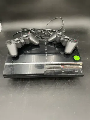 Sony PlayStation 3 original fat model console in black, accompanied by two DualShock 3 wireless controllers and power cord.