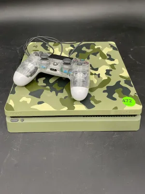 Sony PlayStation 4 Slim console in a green camouflage finish, paired with a clear and white DualShock 4 wireless controller.